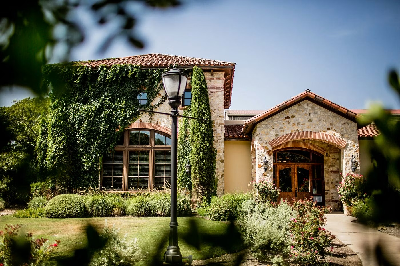 An ivy-covered stone winery framed by gardens in Dripping Springs, Texas Hill Country