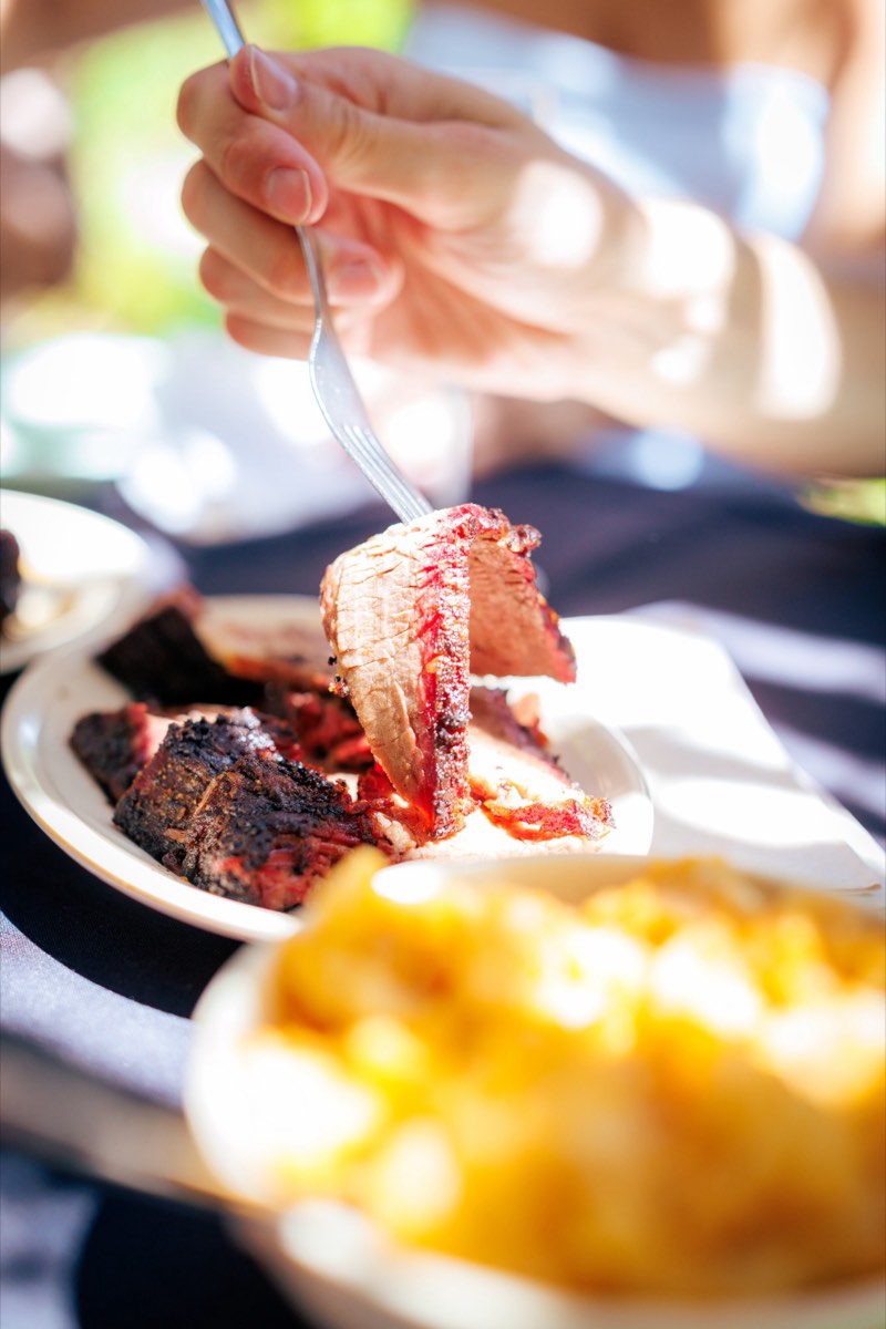 Forkful of smoked brisket over a plate of Texas barbecue