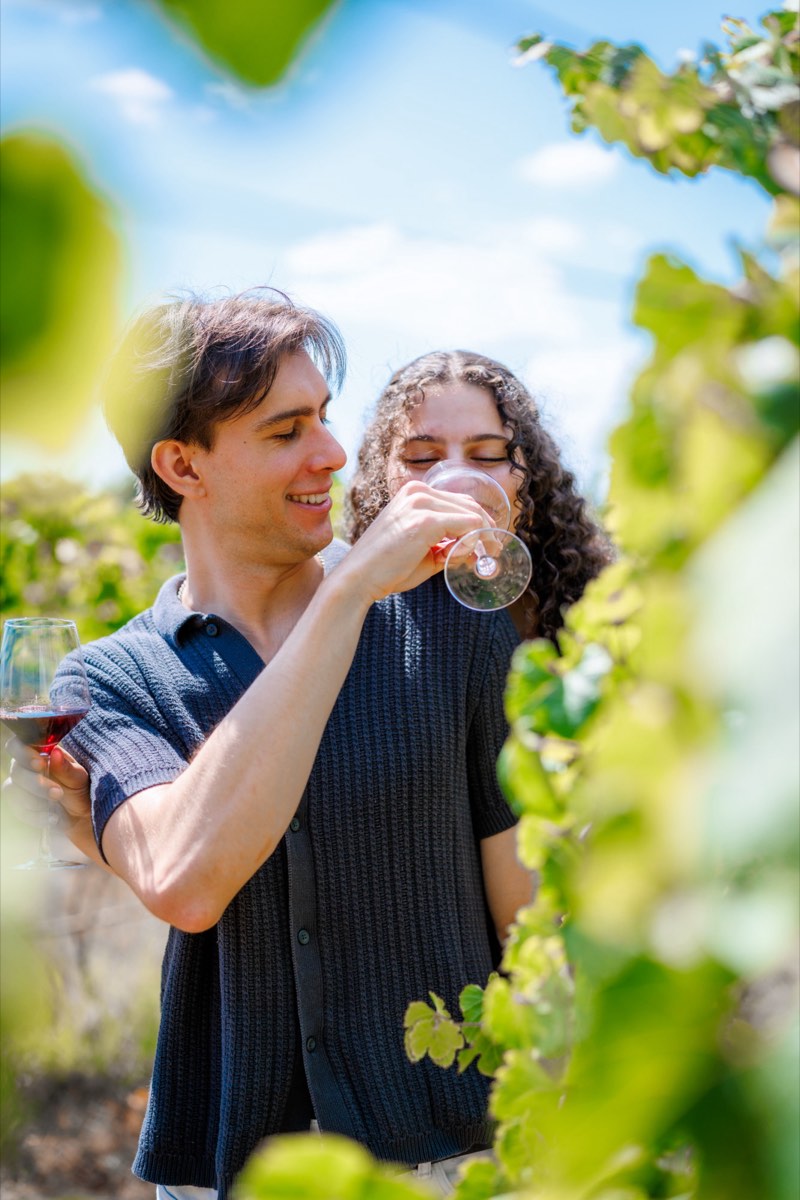 Couple sharing a glass of red wine between the vines